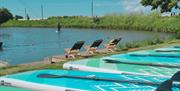 Paddleboards lined up by the calm waters of South Coast Wakepark