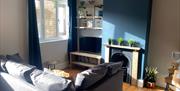 The Beach at the End of the Road - The garden apartment's living space with sofa, fireplace and TV