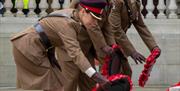 Three people laying poppy wreaths at the Portsmouth cenotaph