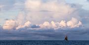 A racing boat in the distance under a clouded sky, copyright Amory Ross - 11th Hour Racing - The Ocean Race