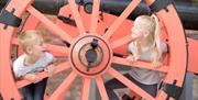 A young boy and girl play inside a large wheel at Fort Nelson