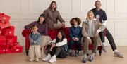 Models on a sofa wearing New Balance clothing and footwear