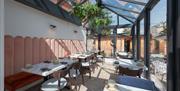 Dining tables set in the Glasshouse of The Garden Restaurant