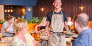 A waiter at Pizza Express brings dishes to a table