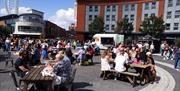 People sitting outside dining on street food at the Gunwharf Quays Plaza