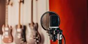 Close-up photograph of a microphone at Southsea Sound, with guitars in the background