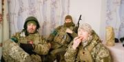 A photograph of three Ukrainian soldiers in military fatigues during downtime.