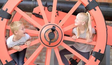 A young boy and girl play inside a large wheel at Fort Nelson