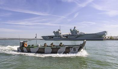 A Falklands F8 Landing Craft at sea, with a QE Class Aircraft Carrier behind