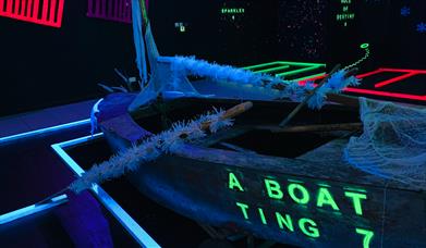 Inside Zingers Adventure Golf, with a boat lit up in UV paint