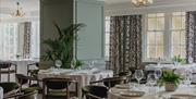 Light and bright dining area at Queens Hotel with light green walls and round tables