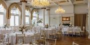 Opulent dining room at Queens Hotel decorated in white and gold