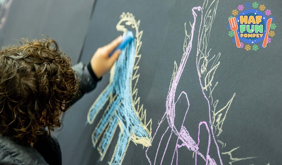 Child drawing a dinosaur with chalk and colouring it in