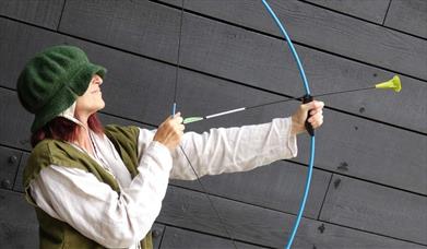 Woman at the Mary Rose museum with a mock bow and arrow