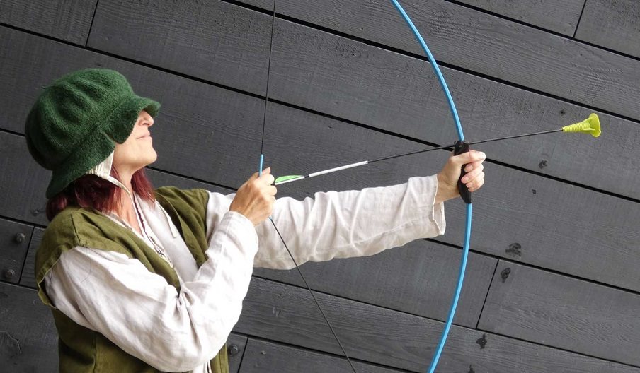 Woman at the Mary Rose museum with a mock bow and arrow