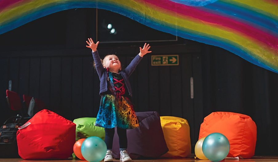 Press shot for Filskit Theatre: Wonder Gigs. featuring a small child listening to music in multicoloured surroundings.