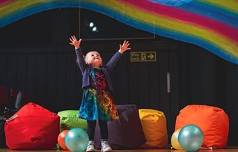 Press shot for Filskit Theatre: Wonder Gigs. featuring a small child listening to music in multicoloured surroundings.