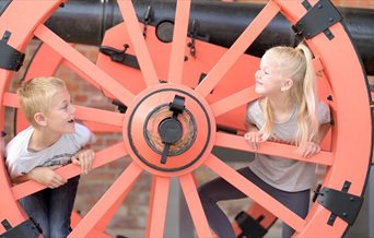 A young boy and girl play inside a large wheel at Fort Nelson