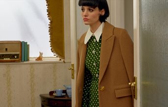 Model wearing a green LK Bennett dress and camel jacket