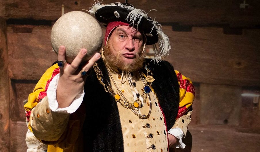 Picture of Henry VIII impersonator holding up a cannon ball.