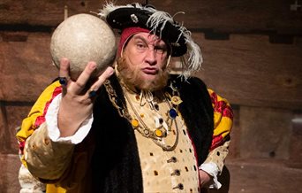 Picture of Henry VIII impersonator holding up a cannon ball.