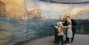 A family looks at a large artwork on display at the National Museum of the Royal Navy