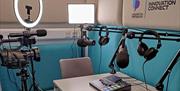 Podcasting studio with all equipment and Innovation Connect logo on the wall