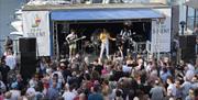 A Queen tribute band take to the stage at Port Solent, watched by an audience of hundreds.