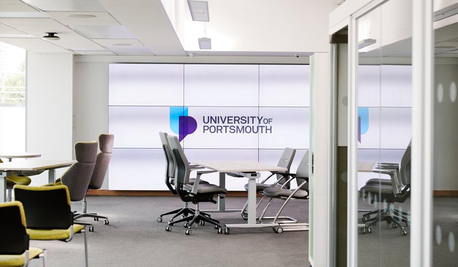 Office space with the University of Portsmouth logo on a window behind
