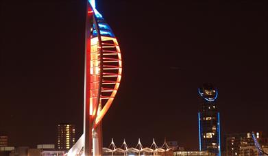 Image of the Spinnaker Tower by night, lit up in red
