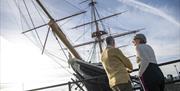 A couple look out over HMS Warrior at Portsmouth Historic Dockyard