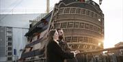 A couple at Portsmouth Historic Dockyard, with HMS Victory in the background