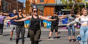 A group takes part in an exercise class in the sunshine at Sweat Festival