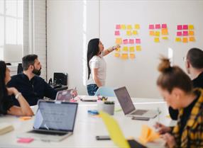 Group of office workers round a meeting room table in a group training session