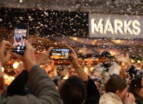 Hands filming Christmassy event on mobile phones outside M&S in Reading