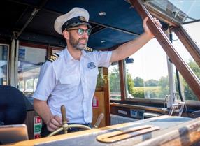 Thames River Cruise captain driving a boat along the River Thames