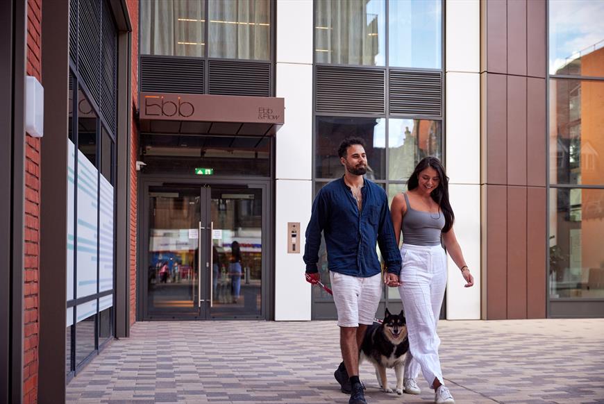 Man, woman and dog walking out of Ebb and Flow building
