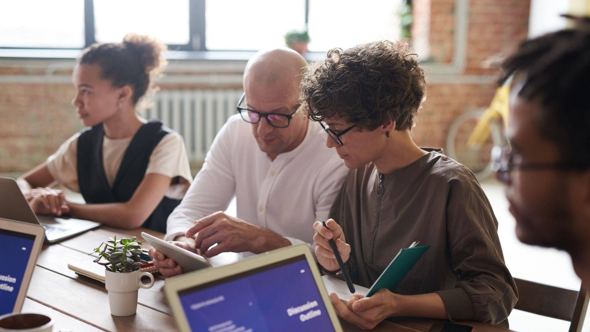 Group of business people, sat around a desk at a meeting