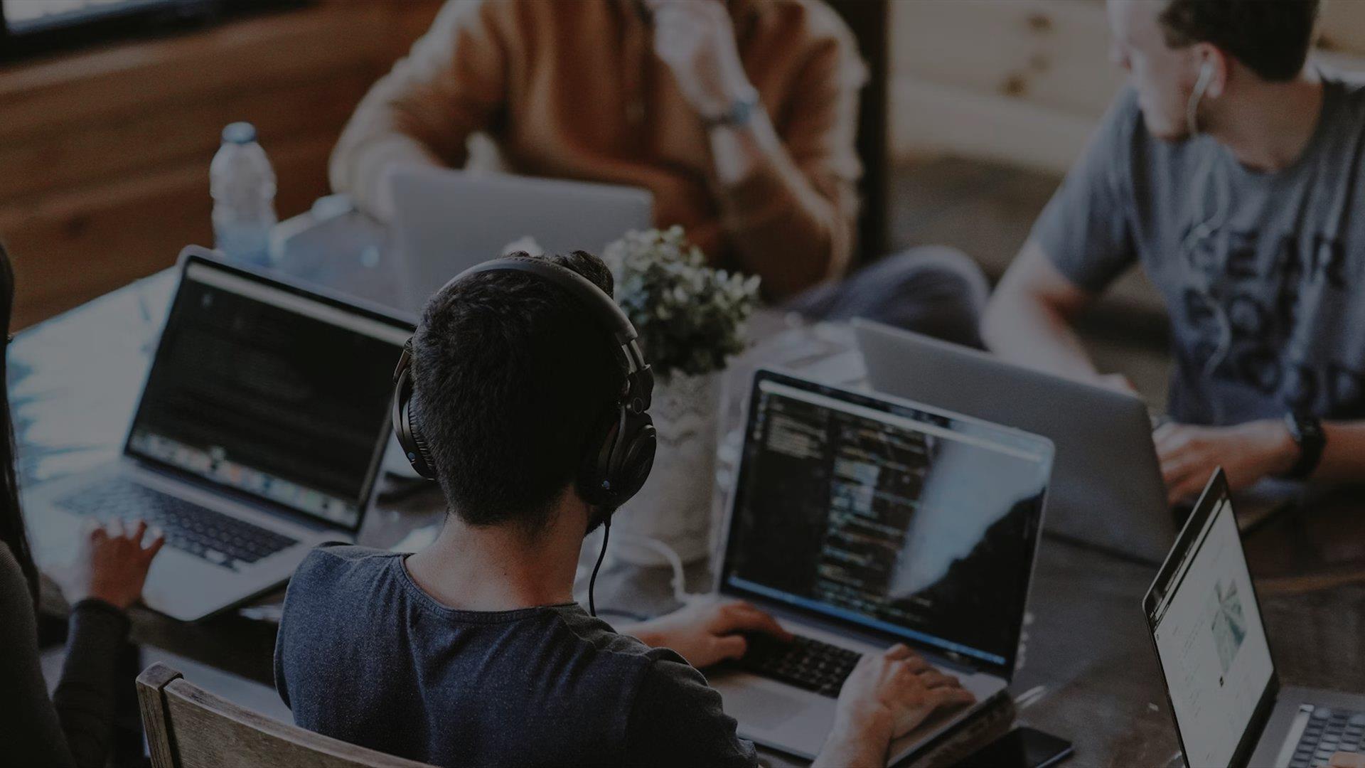 A group on laptops with headphones in