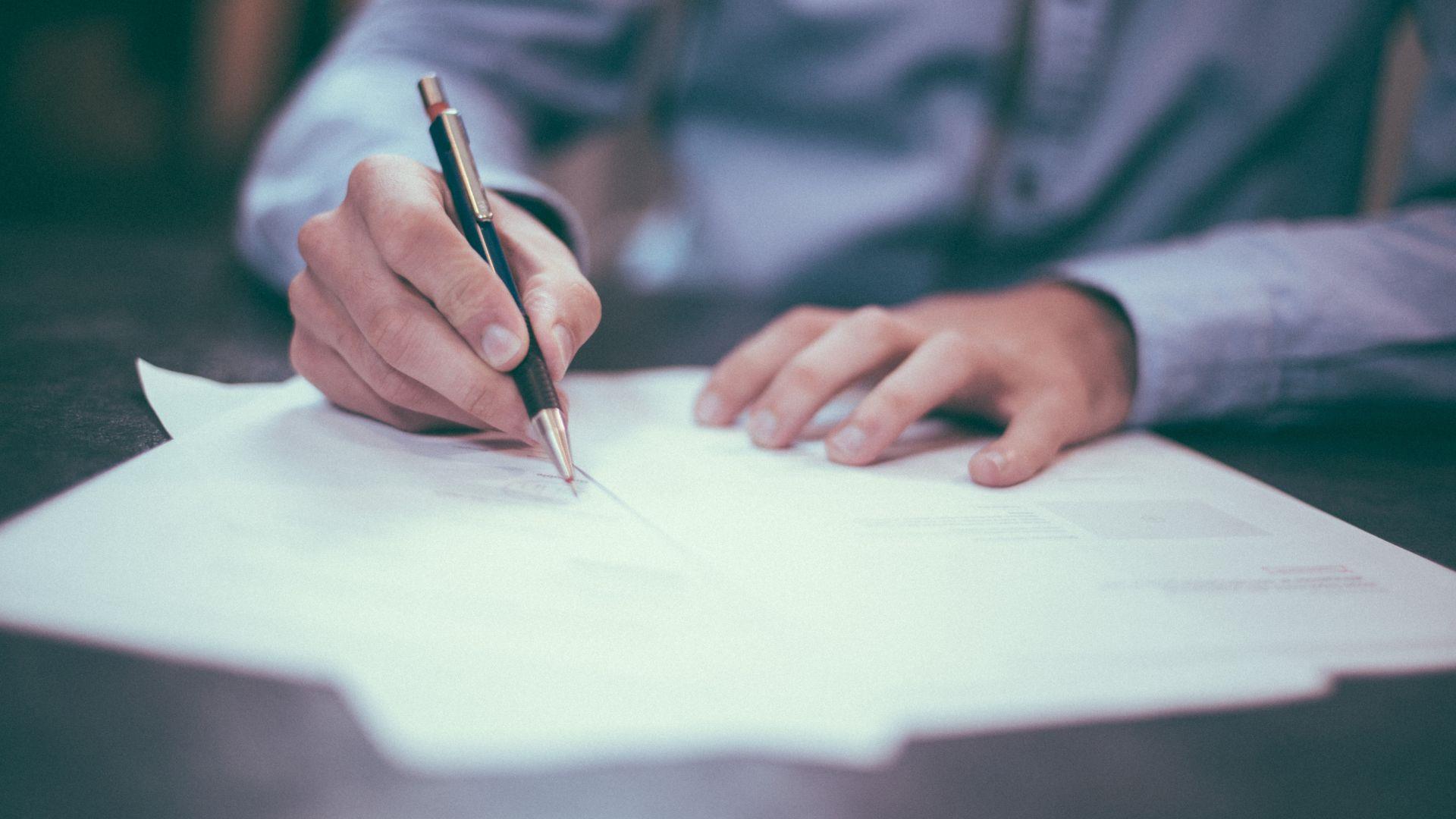 Office man writing on pile of papers