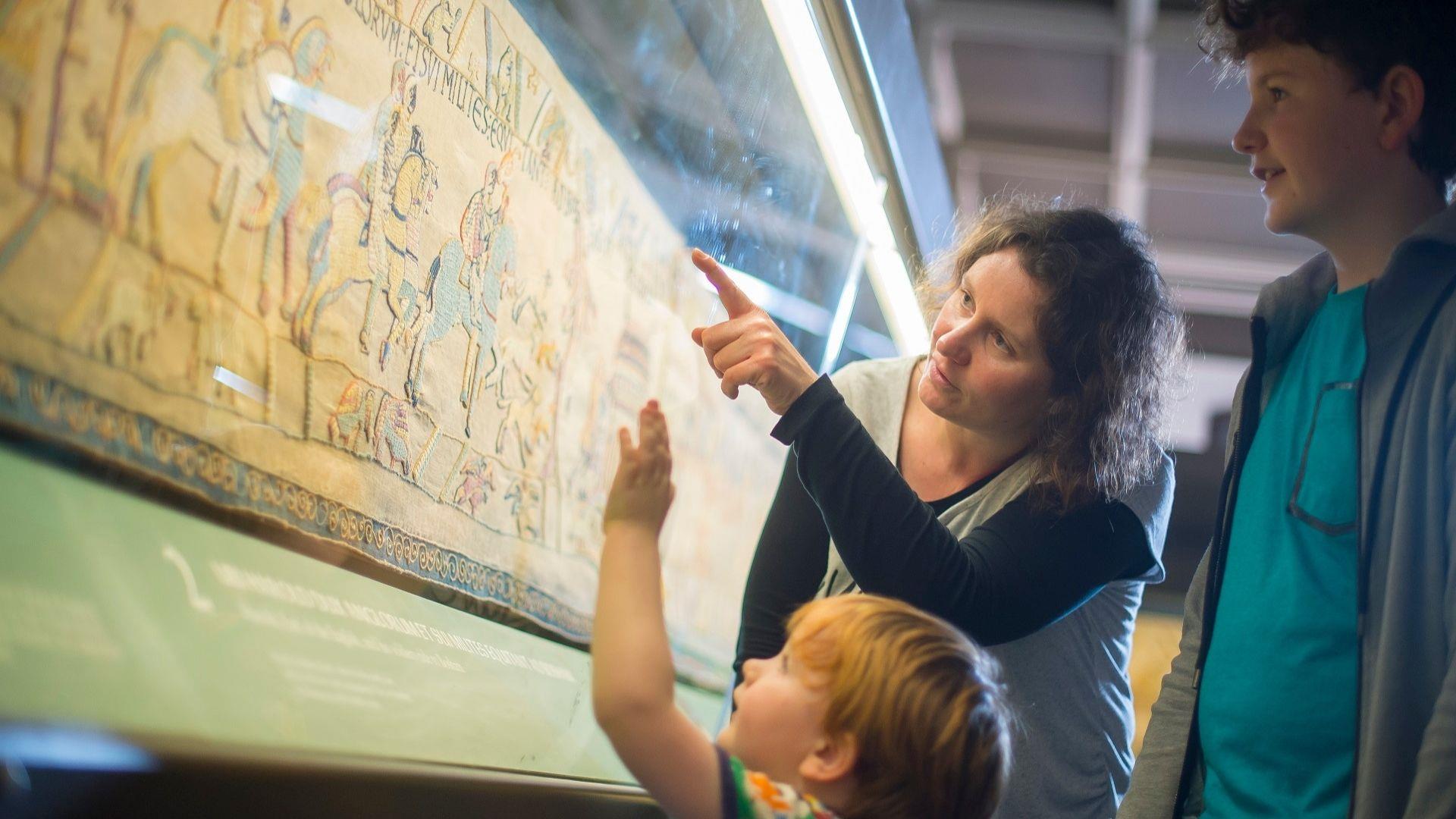 mother and children looking at the Bayeux Tapestry replica