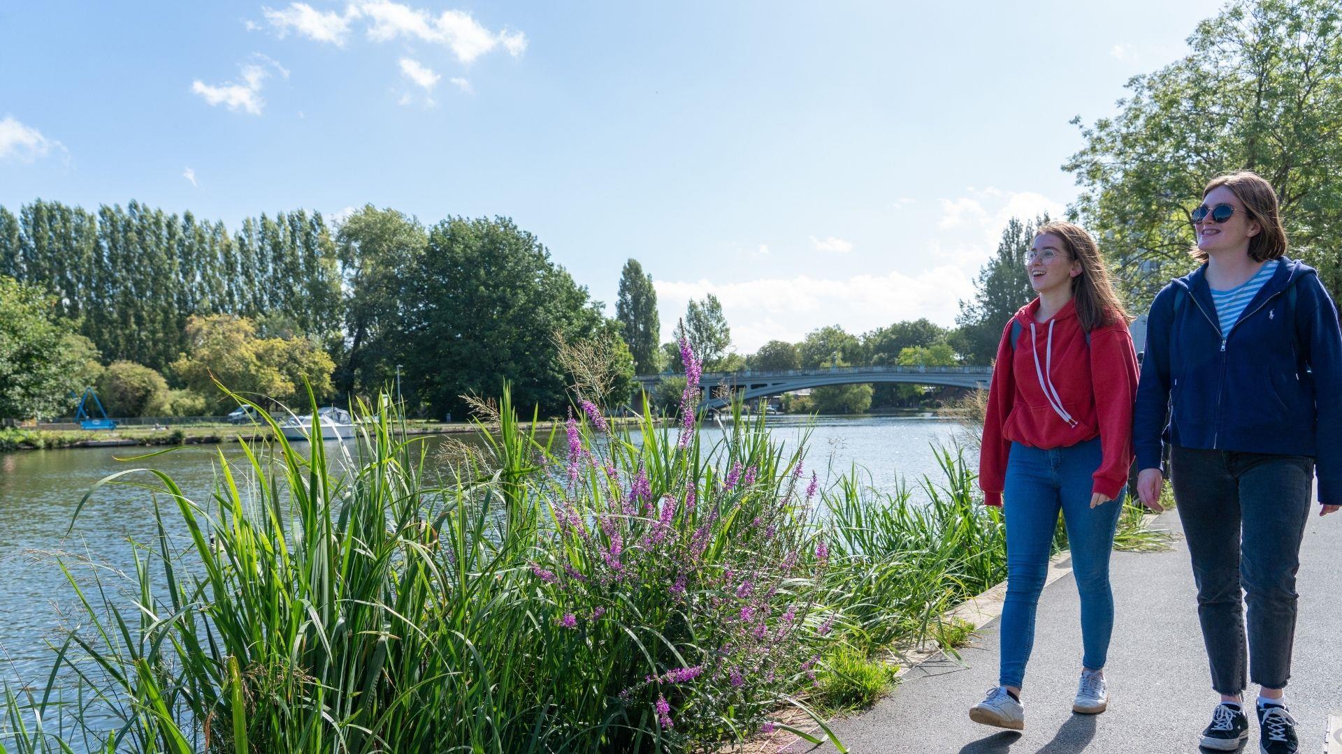 Two girls walking the Thames Path on a sunny day