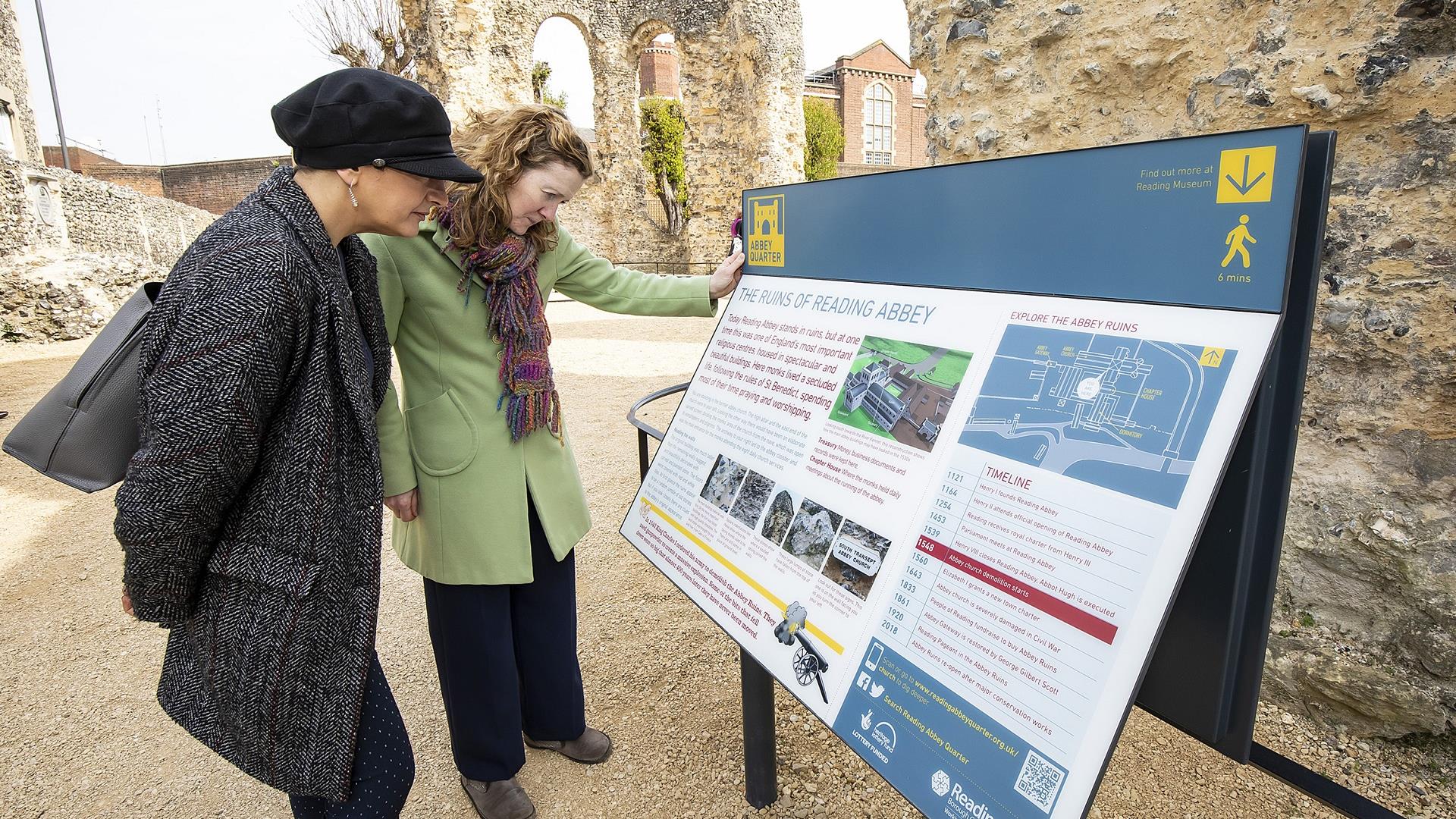 2 people reading an interpretation panel in the ruins of Reading Abbey