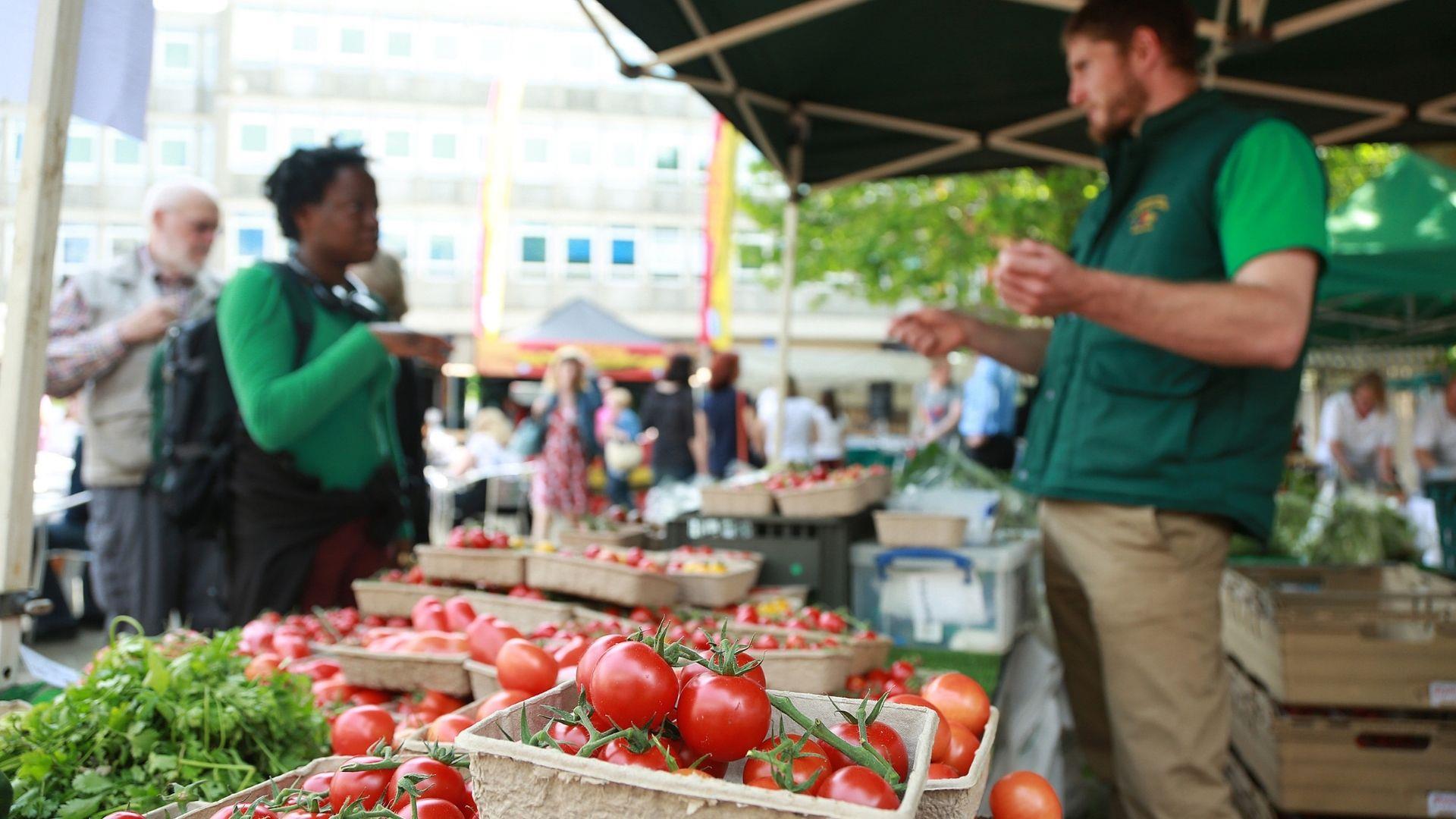 Lady buying vegetables from trader at Reading food markets