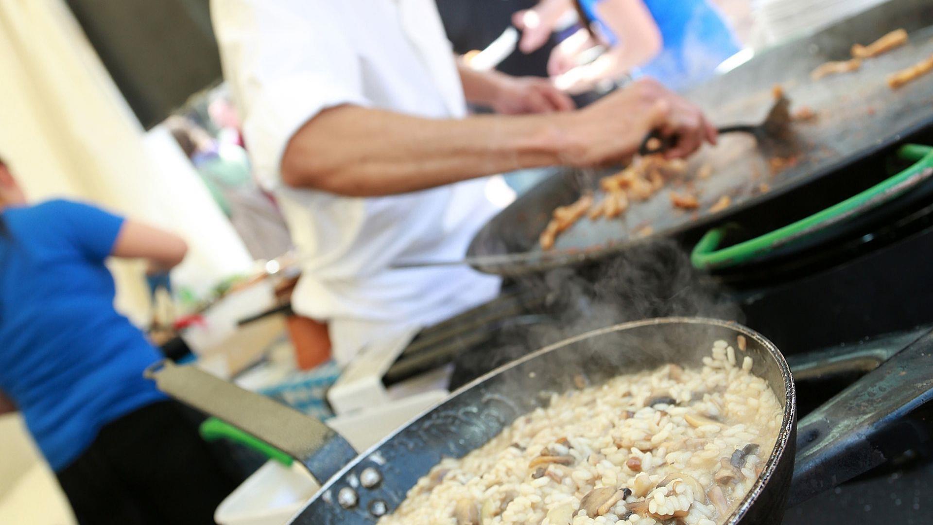 Man cooking and serving street food, cooking on a large skillet.