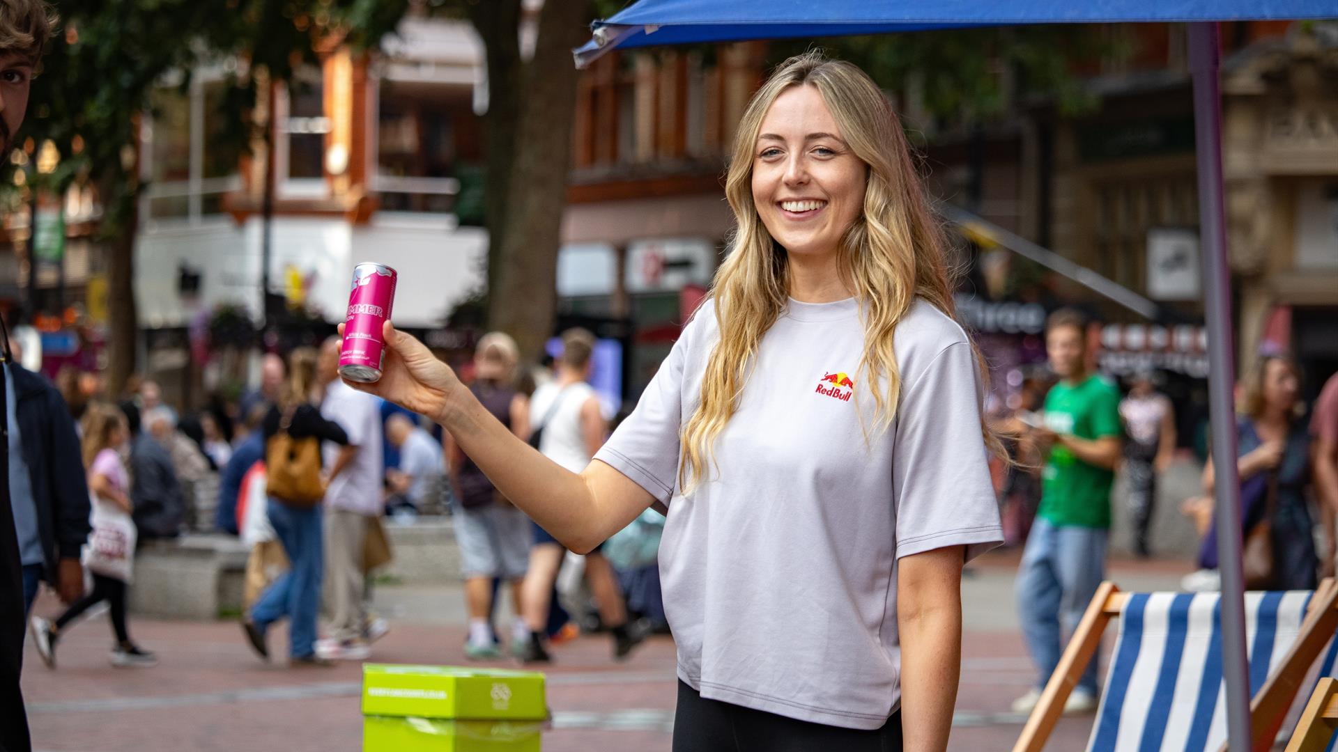 Lady with blonde hair holding can of Red Bull on Broad St in Reading, part of a promotional brand activation stall