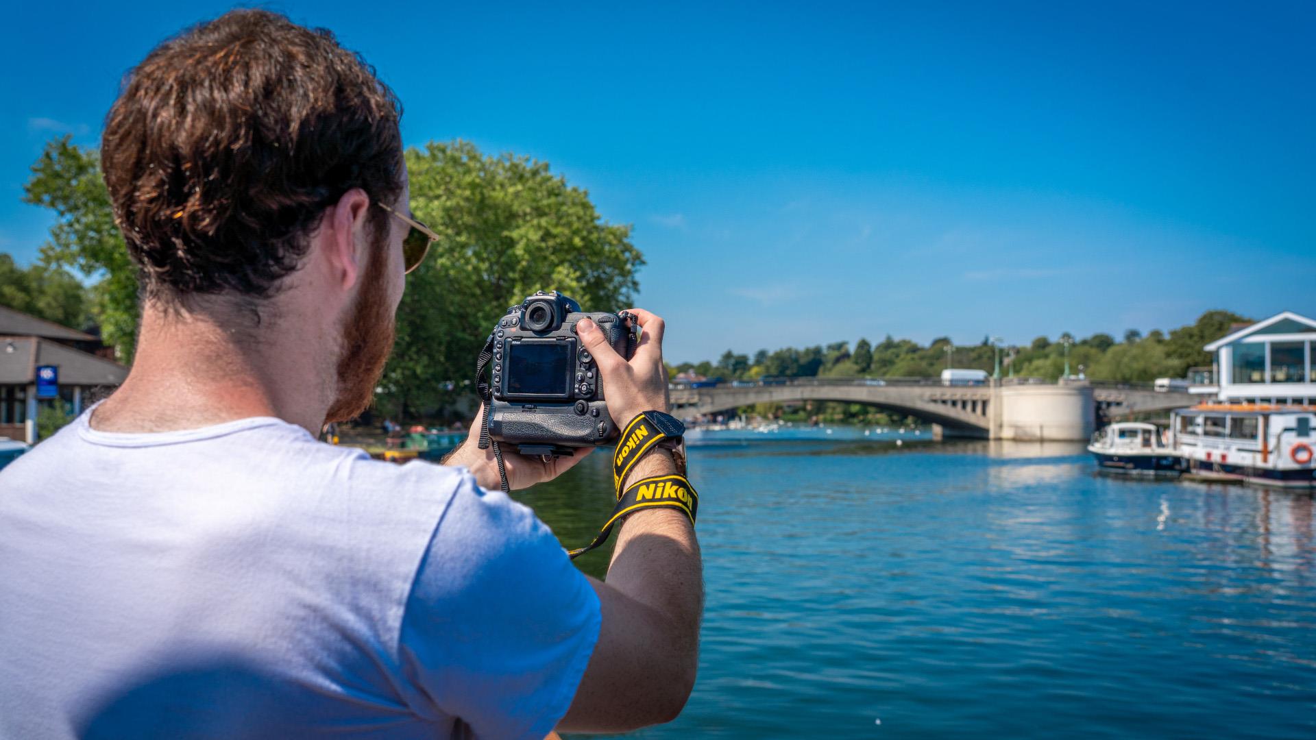 a man taking a photo of the Thames on board a boat.