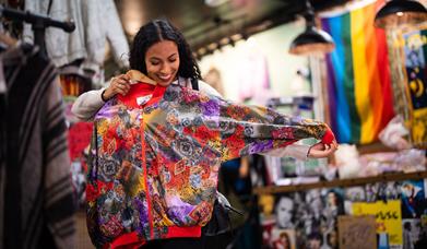 Woman holding up a brightly coloured jacket to herself