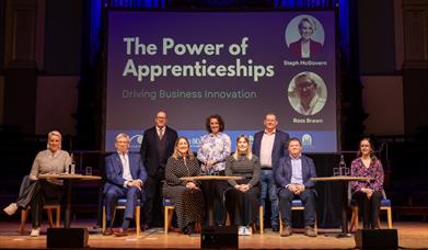 panel posing on stage under powerpoint