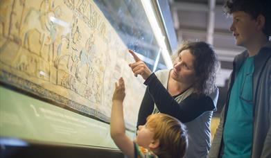 A family looking at the Bayeux Tapestry.